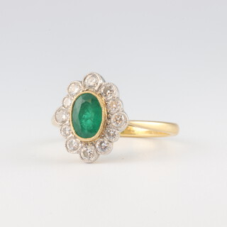 An 18ct yellow gold oval emerald and diamond cluster ring, the emerald approx. 0.75ct, the 12 brilliant cut diamonds each approx 0.03ct, 3.6 grams, size N