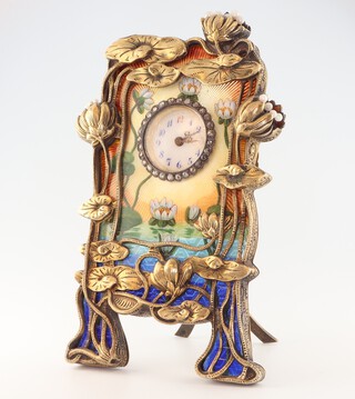 An early 20th Century silver gilt and guilloche enamel Faberge style timepiece with white enamelled dial and red 12, surrounded by paste stones and guilloche enamelled decoration of waterlilies, silver gilt mount, in the form of flowers with seed pearl decoration, having an easel stand bearing a faberge mark and 84 MN the movement marked Rau & Steinmeyer Geneve Pforzheim 12549 10cm 