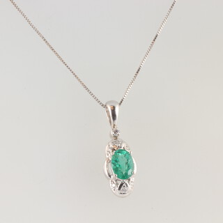 A white gold, stamped 14k, emerald and diamond pendant, the oval cut emerald 0.75ct, hung on a 44cm 14k chain, gross weight 2.8 grams 