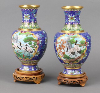 A pair of blue ground cloisonne enamelled club shaped vases decorated storks, together with hardwoods stands, 25cm 