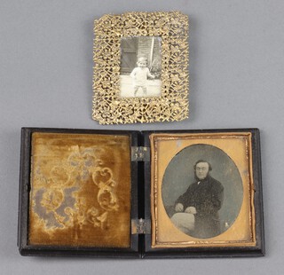 A pierced gilt metal easel photograph frame 9cm x 7cm and an early black and white portrait photograph of a seated gentleman 7cm oval contained in a Bakelite folding case 