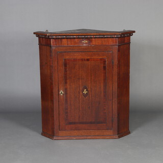 A Georgian oak hanging corner cabinet with moulded cornice, fitted shelves enclosed by a crossbanded and panelled door 91cm h x 84cm w x 57cm d 