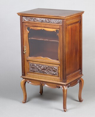 An Edwardian carved walnut music cabinet, fitted shelves enclosed by a glazed panelled door, raised on cabriole supports 94cm h x 55cm w x 37cm d 