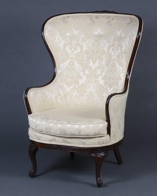 A Victorian mahogany show frame winged armchair upholstered in cream material, raised on carved cabriole supports 114cm h x 69cm w x 50cm d (seat 46cm x 34cm) 