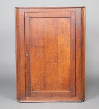 A Georgian oak hanging corner cabinet with moulded cornice, fitted shelves enclosed by a panelled  door, 110cm h x 80cm w x 55cm d 