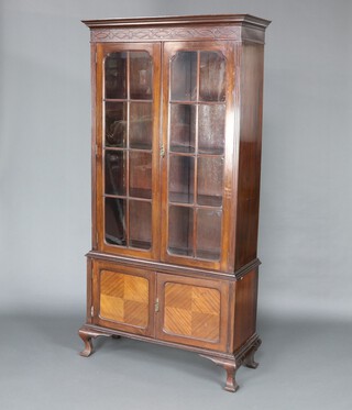 An Edwardian Chippendale style mahogany bookcase on cabinet with moulded cornice and blind fret work frieze, fitted shelves enclosed by astragal glazed doors, the base enclosed by a pair of panelled doors, raised on cabriole supports 194cm h x 96cm w x 38cm d 