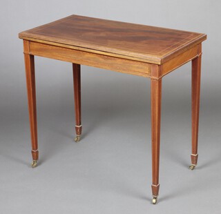 An Edwardian rectangular  inlaid mahogany card table raised on square tapered supports, spade feet and brass casters 76cm h x 83cm w x 47cm d   