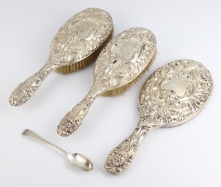 A Victorian repousse silver dressing table set comprising hand mirror and 2 clothes brushes  decorated with masks and birds London 1888, maker William Comyns, together with a teaspoon