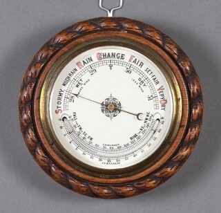 An aneroid barometer and thermometer with porcelain dial, contained in a carved oak case with rope edge 6cm x 19cm 