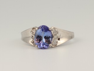 A white gold, testing as 14ct, oval cut tanzanite and diamond ring, the centre stone 1.9ct, the 6 brilliant cut diamonds 0.12ct, size P 1/2, 4.5 grams