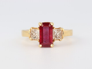 An 18ct yellow gold ruby and diamond ring, the emerald cut centre stone (possibly treated) 2ct, flanked by 2 princess cut diamonds approx. 0.6ct, size. P 6.2 grams 