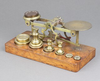 Sampson, Warden & Co, a brass letter scale raised on an oak base together with various weights 