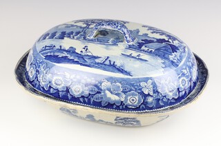 A Victorian blue and white transfer print rounded rectangular dish and cover decorated with an extensive rural scene with figures and buildings 43cm 