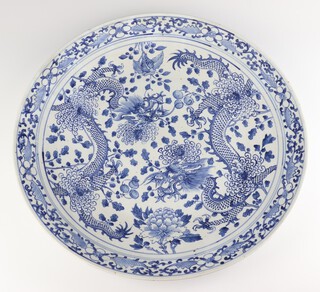 An early 20th Century Chinese blue and white charger decorated with dragons amongst flowers with a floral border 48cm 