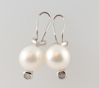 A pair of white gold, testing as 14ct, cultured pearl and diamond earl clips, the pearls 10mm, the diamonds each 0.12ct, 18mm, 5.9 grams 