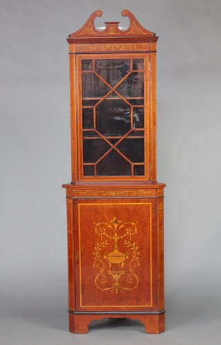 An Edwardian inlaid mahogany double corner cabinet with broken pediment, fitted adjustable shelves enclosed by astragal glazed panelled doors, the base enclosed by inlaid panelled door, raised on bracket feet 207cm h x 66cm w x 48cm d 