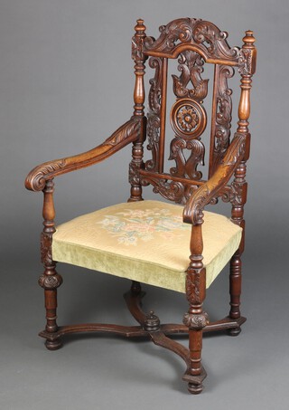 A Victorian Gothic style carved oak open arm chair with pierced carved slat back, upholstered seat, raised on cup and cover supports with X framed stretcher 113cm h x 64cm w x 57cm d (seat 28cm x 33cm) 