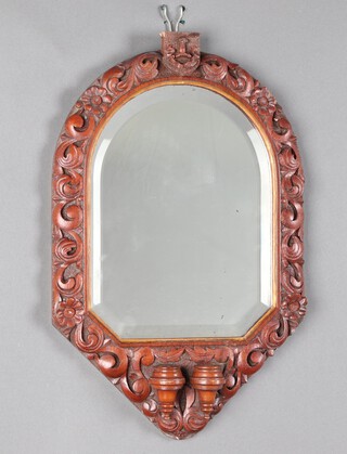 A Victorian arch shaped bevelled plate wall mirror contained in a heavily carved mahogany frame surmounted by a shield with armorial, the base with 2 sconces 47cm h x 30cm w 