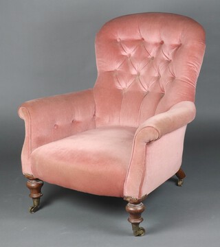 A Victorian armchair upholstered in pink buttoned material, raised on turned supports, brass caps and casters 93cm h x 86cm w x 66cm d (seat 36cm x 49cm) 