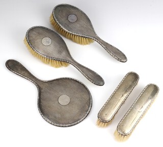 A 5 piece engine turned silver dressing table set comprising hand mirror, 2 hair brushes, 2 clothes brushes, Birmingham 1924 