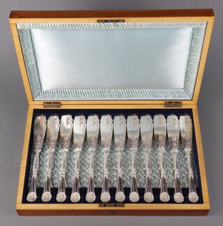 A set of 12 Edwardian silver plated fish eaters with shell grips and engraved decoration in a walnut canteen 