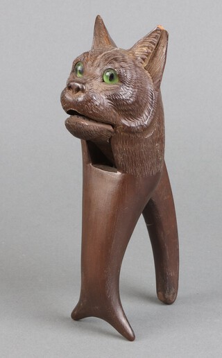 A pair of Black Forrest carved wooden nut crackers in the form of a cats head with green hard stone eyes 19cm 