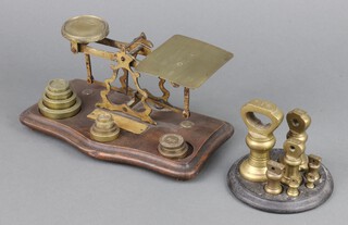 A pair of gilt metal postage scales together with 7 brass bell weights - 1lb, 8 ozs, 4 ozs, 2 ozs, 1 oz, 1/2 oz, 1/4 oz, on an iron stand 