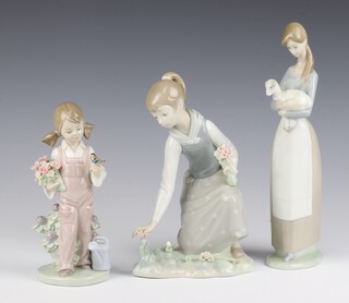 A Lladro figure of a girl holding a bird 5217 18cm, ditto lady picking flowers 21cm and a girl holding a lamb 26cm 