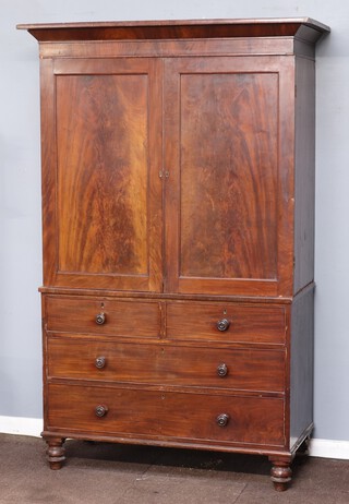 A 19th Century mahogany linen press with moulded cornice, fitted 5 trays enclosed by panelled doors, the base fitted 2 short and 2 long drawers, raised on turned supports 210cm h x 136cm w x 64cm d 