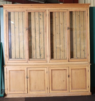 A Victorian stripped and polished pine bookcase on cabinet, the upper section with moulded cornice fitted adjustable shelves enclosed by 2 pairs of glazed panelled doors, the base enclosed by 2 pairs of panelled doors 226cm h x 215cm w x 29cm d  