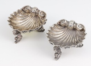 A pair of silver shell shaped salts with dolphin supports London 1925, 66 grams, 6cm 