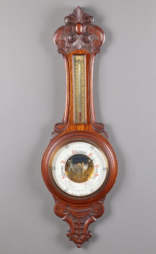 An aneroid barometer and thermometer with porcelain dial, contained in a carved oak case 88cm h x 28cm 