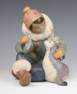 A Lladro matte finished figure of an Eskimo boy feeding a fish to a seal 2361 22cm 