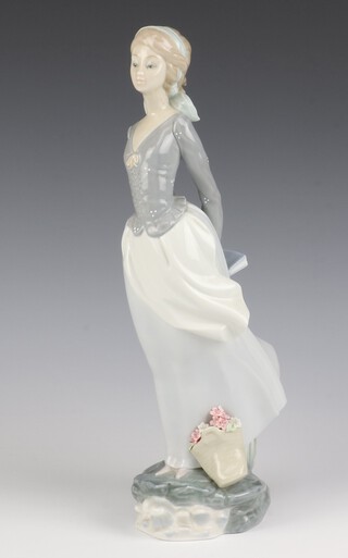 A Lladro figure of a standing lady on a cliff edge holding a book behind her 35cm 