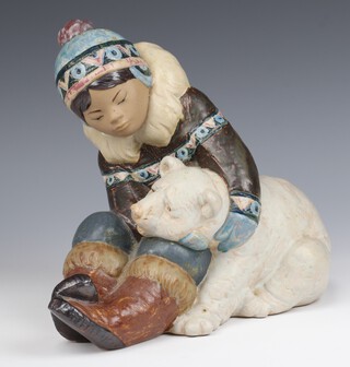 A Lladro matte finished figure of an Eskimo boy holding a polar bear cub 20cm 