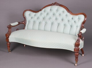 A Victorian carved mahogany show frame sofa with arched back, the seat of serpentine outline, upholstered in turquoise buttoned material, raised on turned supports with ceramic casters 100cm h x 159cm w x 61cm d (seat 127cm x 40cm) 