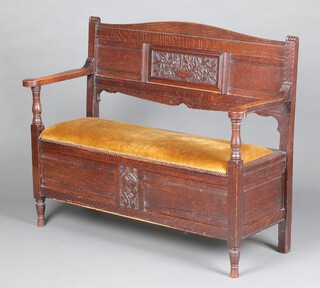 An Edwardian oak settle with carved panel to the back and upholstered hinged seat 90cm h x 117cm w x 44cm d (seat 86cm x 25cm)  