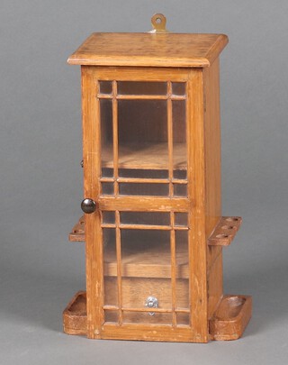 An Edwardian oak smoker's cabinet, fitted a shelf above a drawer, enclosed by a glazed panelled door and with 2 pipe racks to the side 35cm h x 23cm w x 14cm d 