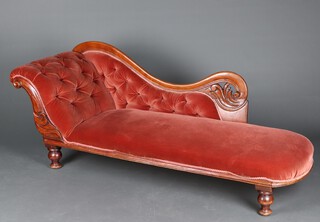 A Victorian carved mahogany show frame chaise longue upholstered in pink buttoned material, raised on turned supports 74cm h x 191cm l x 56cm d (seat 118cm x 36cm)