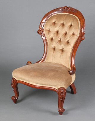 A Victorian carved mahogany show frame nursing chair, the crest carved fruit and upholstered in brown buttoned materials, raised on cabriole supports 90cm h x 58cm w x 47cm d (seat 31cm x 34cm) 