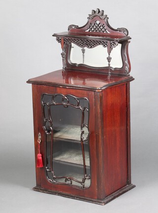 An Edwardian Art Nouveau mahogany music cabinet with raised pierced back fitted a mirror, the base of serpentine outline fitted shelves enclosed by a glazed panelled door 110cm h x 56cm w x 38cm d 