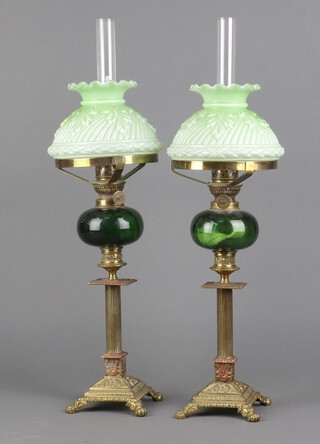 A pair of 19th Century green glass oil lamp reservoirs with clear glass chimneys and opaque green glass shades, raised on gilt columns with square bases with paw feet 56cm h x 17cm 