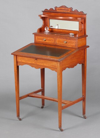 An Edwardian inlaid mahogany Davenport style desk, the raised shaped back fitted a mirror above pen recess, 2 associated inkwells and 2 drawers, the fall front revealing a fitted interior with pigeon holes, raised on square tapered supports with H framed stretcher, brass caps and ceramic casters 115cm h x 60cm w x 51cm d 