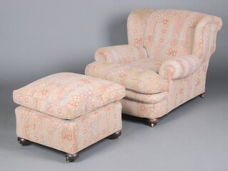 A Howard style winged armchair upholstered in tapestry material 78cm h x 86cm w x 95cm d (seat 37cm x 46cm)  together with a matching footstool, raised on bun feet 26cm h x 60cm 