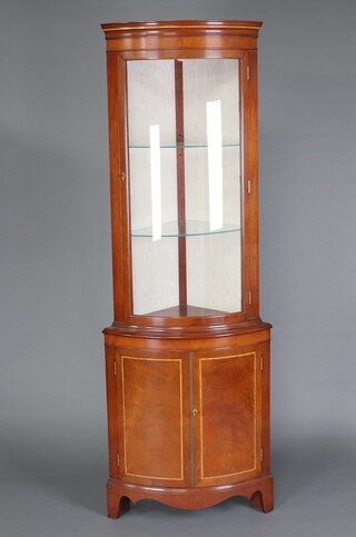 A Regency style inlaid mahogany bow front double corner cabinet fitted shelves enclosed by a glazed panelled door 102cm h 