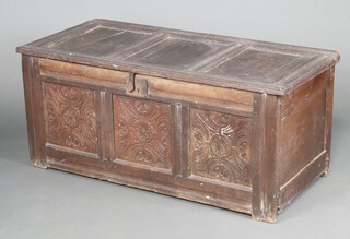 A 17th Century carved oak coffer of panelled construction with hinged panelled lid and iron lock front, the front 3 panels are carved flower head roundels, 56cm h x 130cm w x 60cm d 