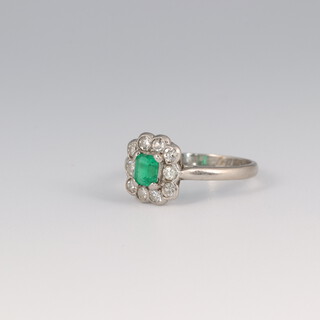 A 14ct white gold emerald and diamond cluster ring, the emerald 0.25ct, the brilliant cut diamonds 0.30ct, size I, 2.8 grams
