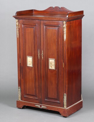 An Edwardian Empire style mahogany cabinet with 3/4 gallery, fitted shelves enclosed by panelled doors and with gilt metal mounts to the side and 2 small landscape prints to the centre of the door 125cm h x 75cm w x 43cm d 