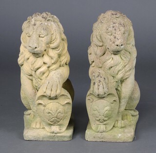 A well weathered pair of garden statues/gate post caps  in the form of seated lions with shields 54cm h x 32cm w x 20cm d 