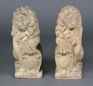 A well weathered pair of garden statues/gate post caps in the form of seated lions with shields 54cm h x 32cm w x 20cm d